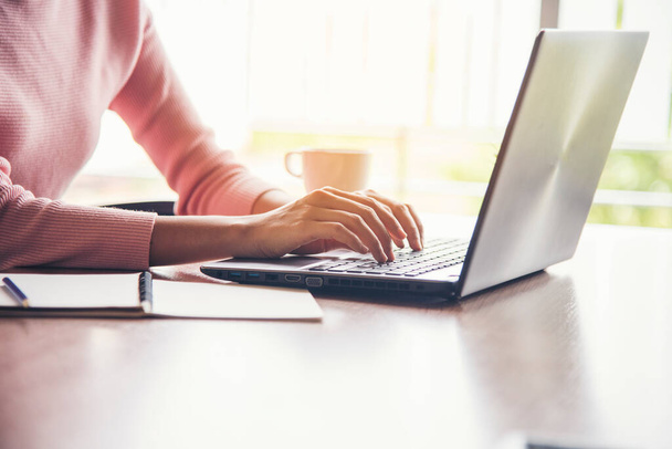 Egy nő, aki otthonról dolgozik a laptopon, online megbeszélés az irodában. Vállalkozó ázsiai üzletasszony segítségével notebook laptop ülni kanapé technológia új normális életmód. Boldog nő gépelés billentyűzet laptop - Fotó, kép