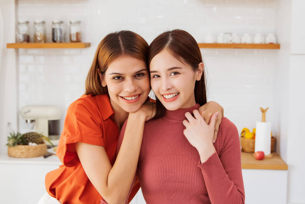 Portrait pose up happy LGBT lesbian couple healthy colorful shirts vibrant in kitchen at home spending time cooking together multiracial lesbian couple living proud charming smile looking at camera. - Photo, Image