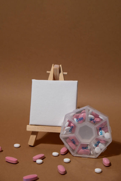 Sluiten van medische pil doos met doses tabletten voor dagelijks gebruik neem medicijnen met witte roze drugs en capsules met papieren notitie Kopieer ruimte voor uw tekst template mock up. Dagelijkse vitaminen thuis - Foto, afbeelding