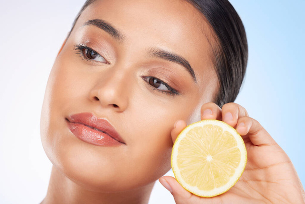 Beauty, lemon and face of studio woman with citrus fruit for organic anti aging treatment, facial detox or aesthetic cosmetics. Vitamin C benefits, spa wellness and self care model on blue background. - Photo, Image