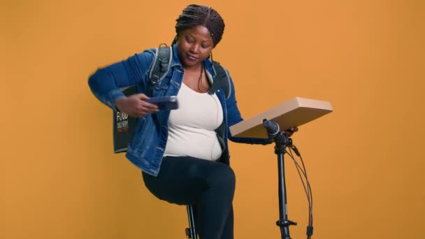 African American courier παραδίδει το πακέτο χρησιμοποιώντας ποδήλατο και σύγχρονη μηχανή pos εξασφαλίζοντας την επαφή-ελεύθερη υπηρεσία. Γυναίκα παράδοσης που παρέχει το τερματικό NFC για την κατάλληλη ασύρματη πληρωμή για την παράδοση τροφίμων. - Πλάνα, βίντεο