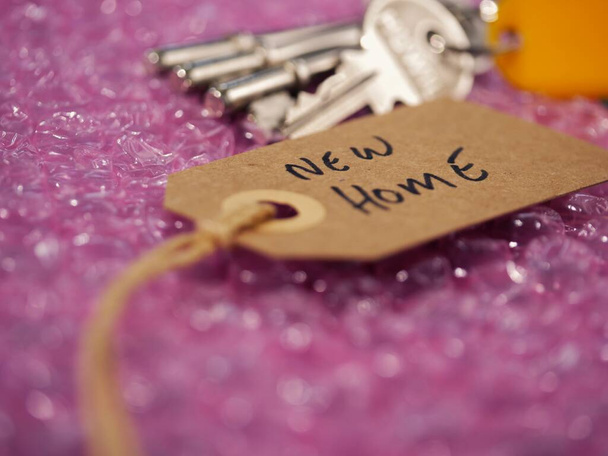 Blasenwickel und braunes Adressetikett mit Schlüsseln zum neuen Zuhause in Nahaufnahme - Foto, Bild