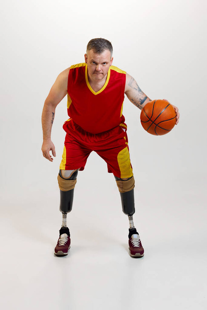 Çekici, kendine güvenen, protez bacaklı, turuncu basketbol topuyla hareket eden bir adam. Engelli insanlar için özel bir spor. Spor, oyuncu, sağlık, vücut bakımı kavramı. - Fotoğraf, Görsel