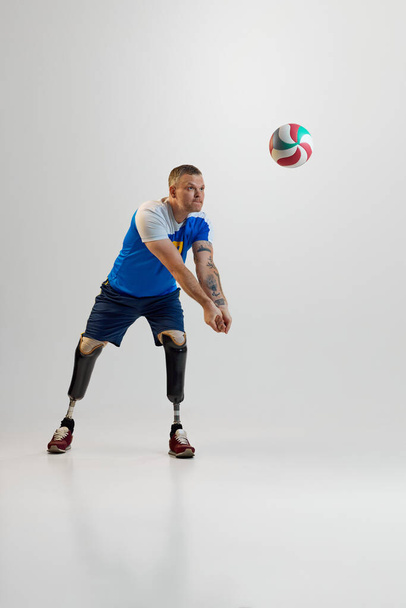 Pewny siebie młody człowiek z protezą nóg niepełnosprawność stoi uderza w siatkówkę w ruchu. Sport integracyjny dla osób niepełnosprawnych. koncepcja sportu, zawodnika, medycyny, zdrowia, pielęgnacji ciała. - Zdjęcie, obraz
