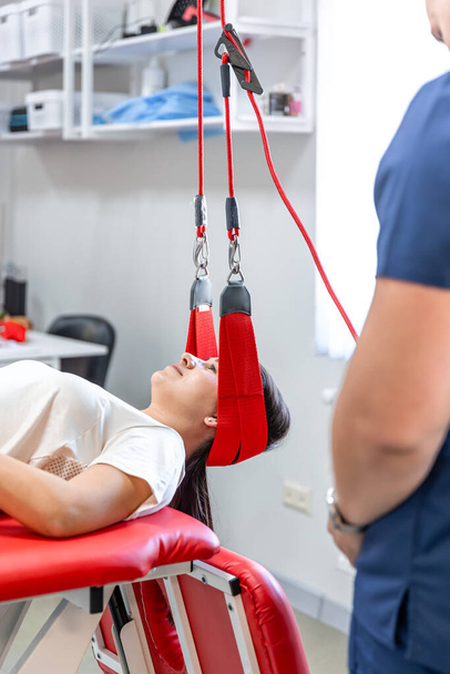 Γυναίκα ασθενής σε διαθεσιμότητα στο κέντρο αποκατάστασης. Θεραπευτικές ασκήσεις και νευρομυϊκή ενεργοποίηση σε ιμάντες κόκκινου λώρου, τεχνική Neurac. - Φωτογραφία, εικόνα