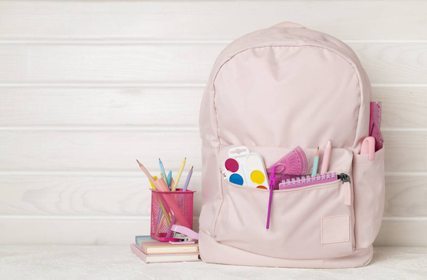 Mochila escolar rosa con papelería en mesa de madera - Foto, Imagen