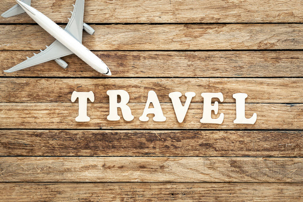 Word Travel e avião em fundo de madeira, vista superior. - Foto, Imagem