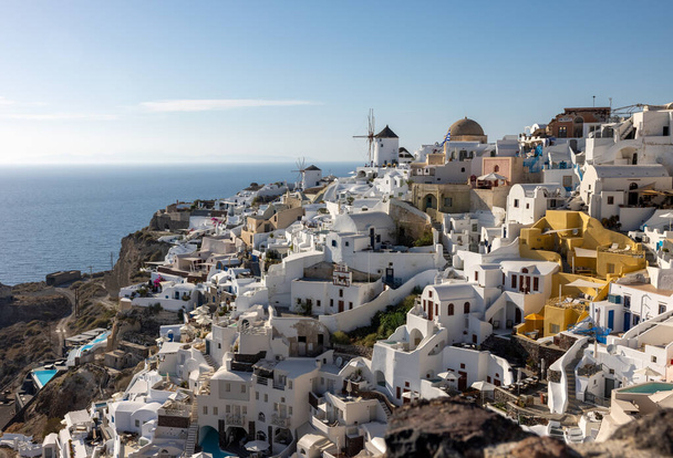 Oia, Santorini, Görögország - 2021. június 28.: Fehérre meszelt házak és szélmalmok Oiában, Santorini szigeten, Kerékpárok, Görögország - Fotó, kép