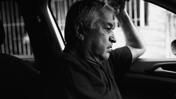 Osamělá starší osoba v zoufalé situaci, bojující v tichém zoufalství uvnitř zaparkovaného auta, dramatické monochromatické, černobílé - Fotografie, Obrázek