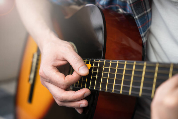 A young man with mediator playing guitar. Close-up. Selective focus. - Photo, Image