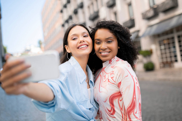 Πορτρέτο της χαρούμενες πολυεθνικές φίλες λαμβάνοντας Selfie στο Smartphone Outdoors, Happy Young Beautiful Women Posing On City Street, Θετικές Besties Διασκεδάζοντας μαζί, Κάνοντας Φωτογραφίες, Closeup - Φωτογραφία, εικόνα