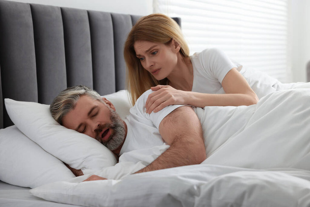 Irritated woman waking up her snoring husband in bed at home - Photo, image