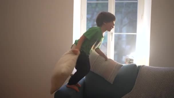 Večerní zábava mladého chlapce potápění do gauče s polštáři doma - Záběry, video