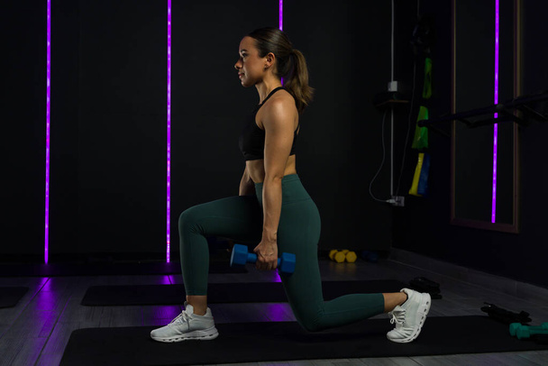 Фітнес жінка робить вправи з легенями, використовуючи ваги гантелі під час роботи з функціональними тренуваннями у фітнес-центрі високого класу - Фото, зображення