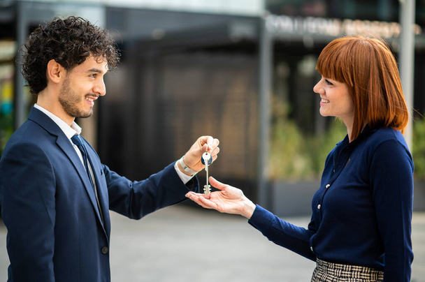 Businessman giving the keys of a new office to a businesswoman, real estate sale concept - Fotó, kép