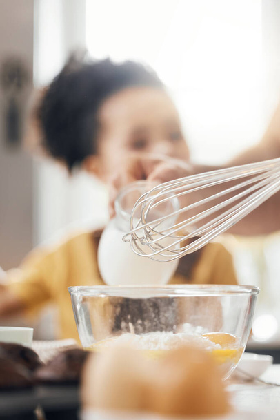 Whisk, egg and kitchen in closeup, kid and learning with muffins, cooking and helping hand from parents. Bowl, flour and child with development, teaching and baking with milk, cupcakes or family home. - Photo, Image