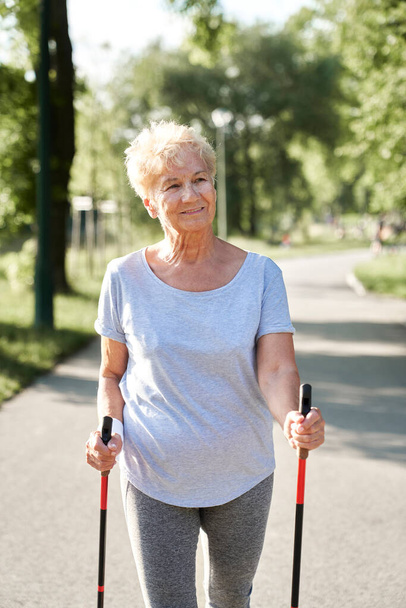 Porträt einer Seniorin beim Nordic Walking im Park - Foto, Bild