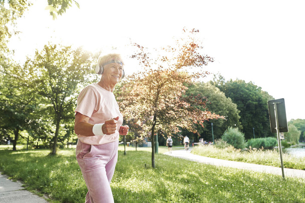 Senior woman exercising in the park in the summer - 写真・画像