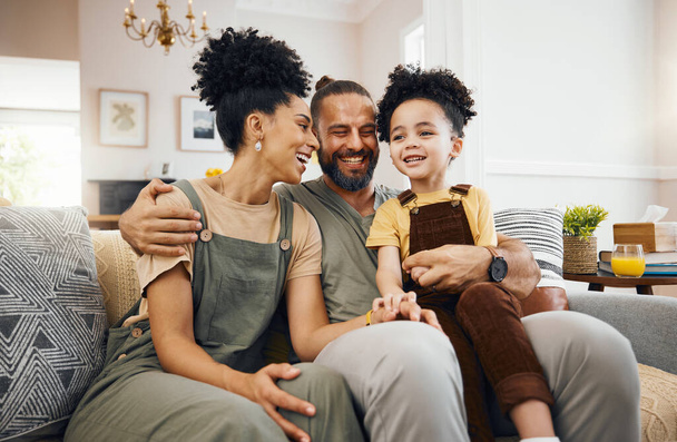 Χαμογελάστε, χαλαρώστε και μια διαφυλετική οικογένεια στον καναπέ για συζήτηση, αγάπη και δέσιμο. Ευτυχισμένος, το σπίτι και μια μητέρα, ο πατέρας και ένα παιδί αγόρι στον καναπέ για ομιλία, φροντίδα και μαζί για την επικοινωνία. - Φωτογραφία, εικόνα