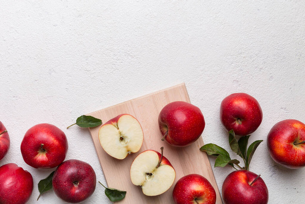 Fresh red apples with green leaves on table. cutting board with knife. Top view. - Photo, Image