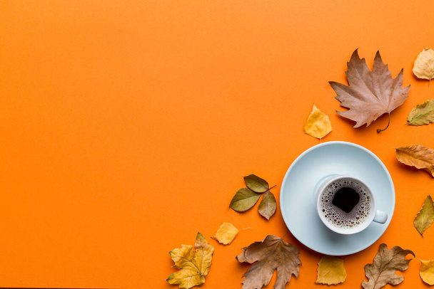 Composición laica plana con colorida taza de café de otoño y hojas sobre un fondo de color. vista superior. - Foto, imagen