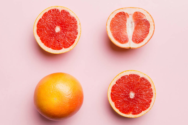 ジューシーなグレープフルーツのスライスを色の背景に新鮮なフルーツグレープフルーツ。最上階だ。コピースペース。創造的な夏のコンセプト。コピースペースと最小限のフラットレイアウトで柑橘類の半分. - 写真・画像