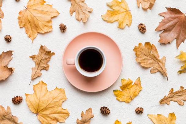 Composición laica plana con colorida taza de café de otoño y hojas sobre un fondo de color. vista superior. - Foto, imagen