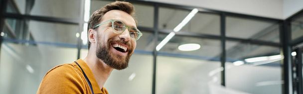 professioneller Kopfschuss eines überglücklichen bärtigen Geschäftsmannes mit Brille in zeitgenössischem Büro - Foto, Bild