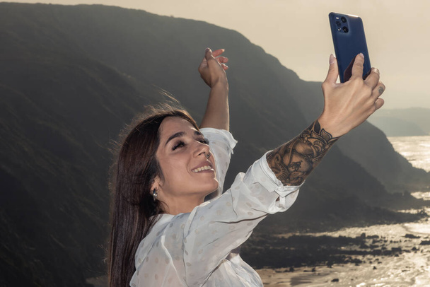 Bruneta žena zachycuje ohromující útesu pohled s jistotou a tetovaný styl - Fotografie, Obrázek