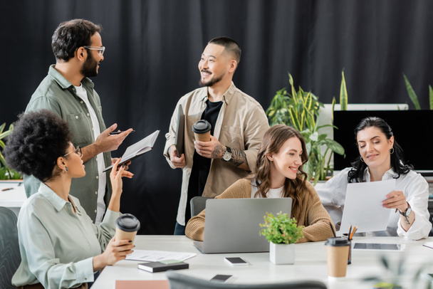 fröhliches multiethnisches Business-Team, das Ideen generiert und Startup-Projekt im Coworking diskutiert - Foto, Bild