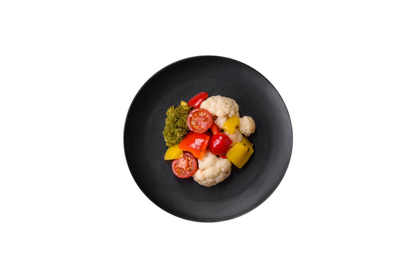 Πεντανόστιμη φρέσκια σαλάτα μπρόκολο, κουνουπίδι, γλυκοπιπεριές και ντοματίνια με μπαχαρικά και αλάτι σε σκούρο μπετόν φόντο - Φωτογραφία, εικόνα
