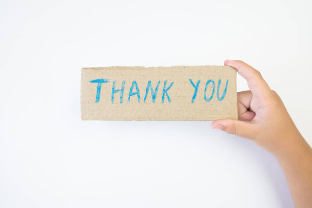 Een hand houdt een kartonnen doos vast met een bedankbriefje. Wees dankbaar voor een gunst of hulp. Iemand zegt dank je aan iemand.. - Foto, afbeelding