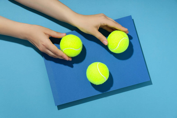 Manos femeninas y pelotas de tenis sobre fondo azul bicolor - Foto, Imagen