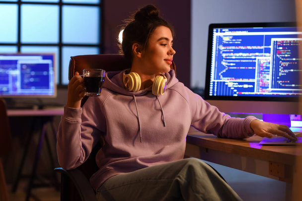 Nuori naisohjelmoija juo kahvia työskennellessään toimistossa - Valokuva, kuva