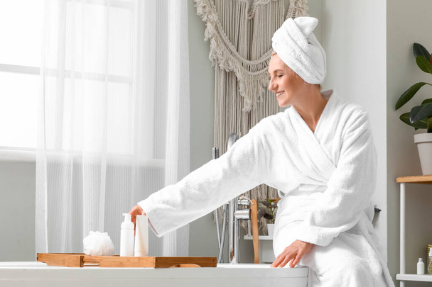 Dojrzała kobieta z ręcznikiem siedzi w łazience - Zdjęcie, obraz