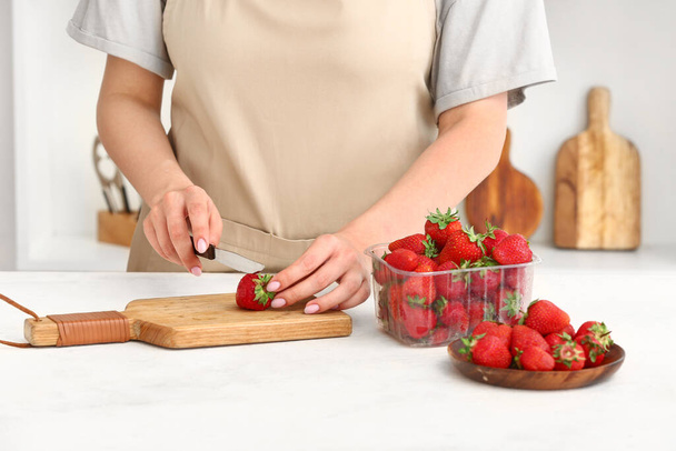Mujer cortando fresas maduras en la mesa en la cocina - Foto, imagen