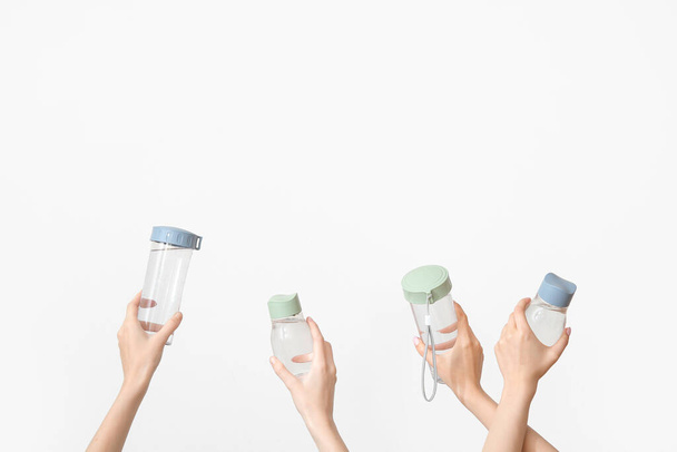 Manos femeninas con botellas de agua dulce sobre fondo claro - Foto, imagen