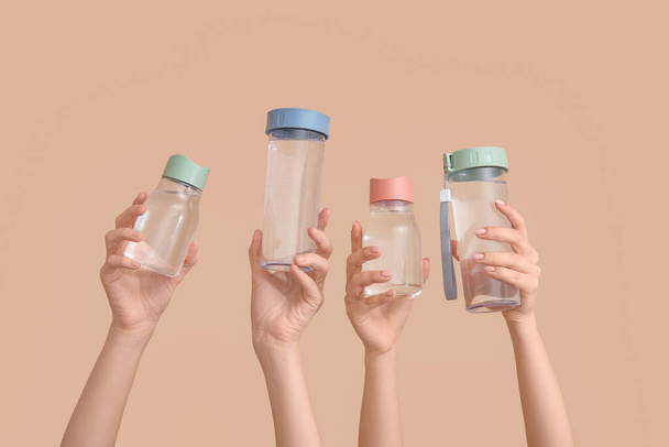 Manos femeninas con botellas de agua fría sobre fondo beige - Foto, imagen