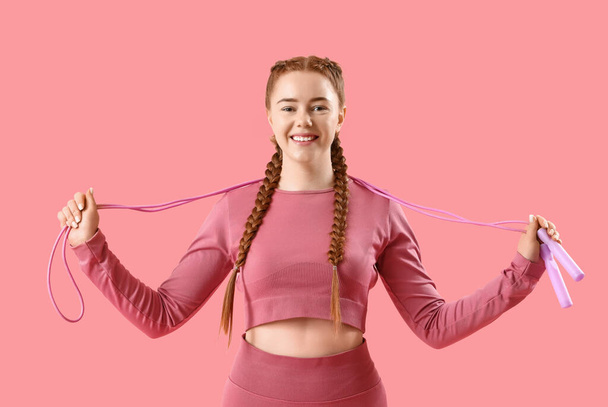 Спортивна молода жінка з пропусканням мотузки на рожевому фоні - Фото, зображення