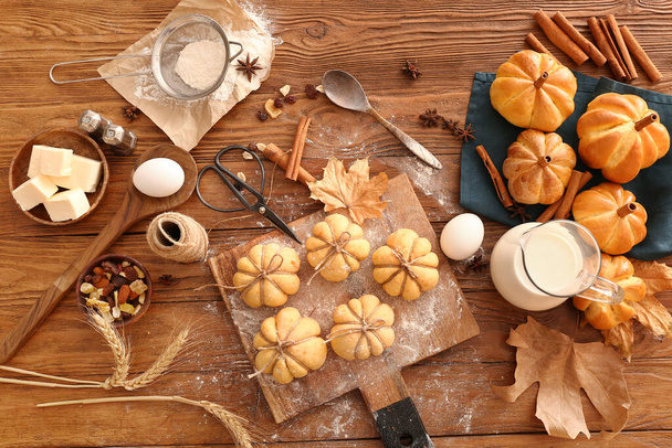Board with pumpkin shaped buns and ingredients on wooden background - Photo, Image