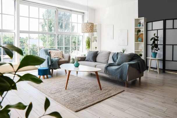 Интерьер светлой гостиной с креслом, серым диваном и журнальным столиком - Фото, изображение