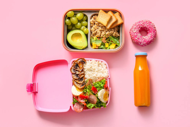 Almuerzos con diferentes deliciosos alimentos y botella de jugo sobre fondo rosa - Foto, Imagen