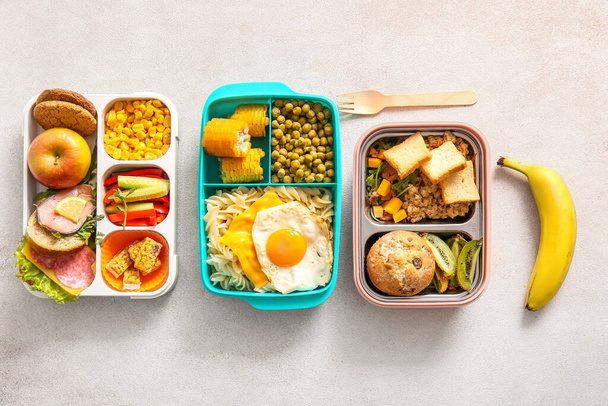 Cajas de almuerzo con diferentes deliciosos alimentos sobre fondo claro - Foto, Imagen