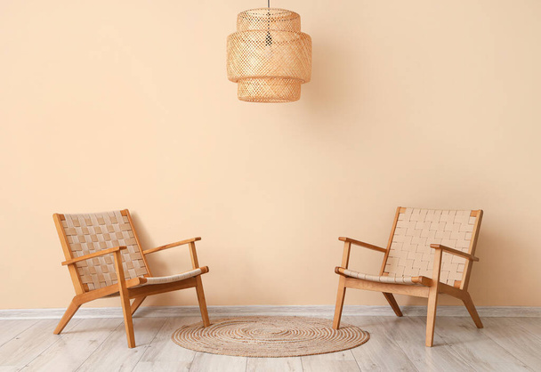 Bej duvarın yanında hasır koltuklar ve lamba - Fotoğraf, Görsel