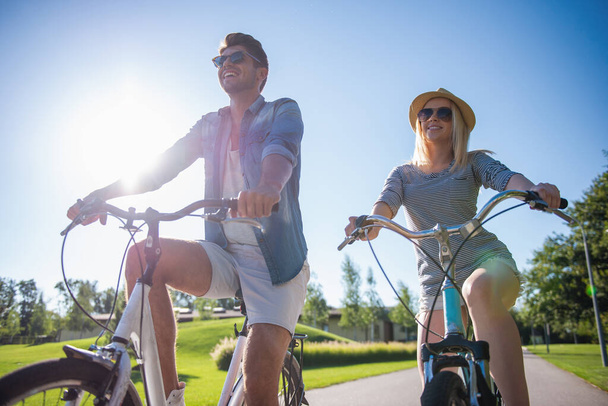 Beau couple parle et sourit en faisant du vélo dans le parc
 - Photo, image