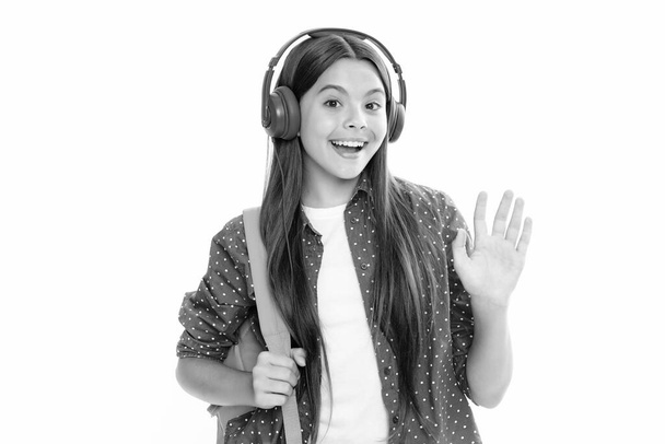 Шкільна дівчина в навушниках на ізольованому студійному фоні. Шкільна та музична концепція. Портрет щасливої усміхненої дівчинки-підлітка
 - Фото, зображення