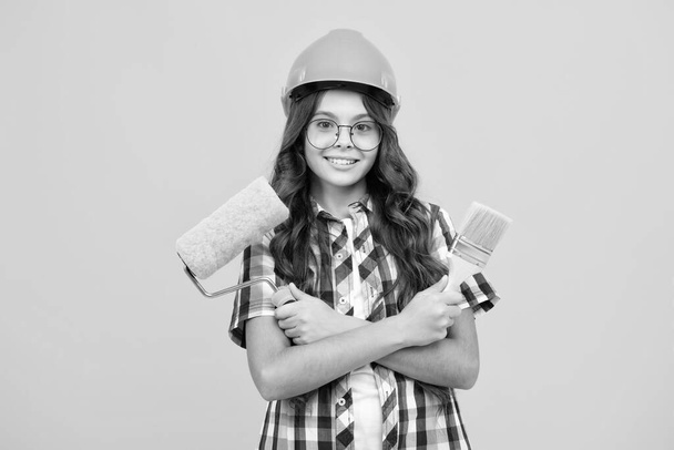 Teenager child painter in helmet with painting brush. Child in hard hat. Kid builder painter on construction site. Renovation and repair - Foto, Imagen