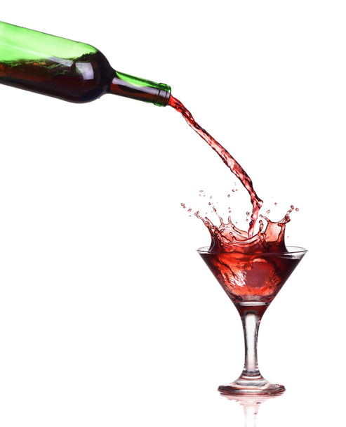 Red wine splash in the glass, pouring from a bottle - Photo, Image