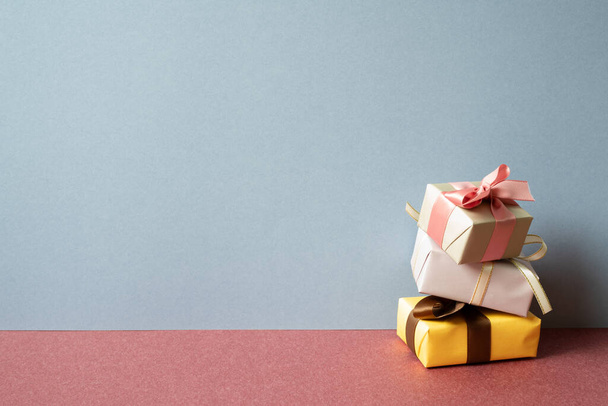 Montón de caja de regalo de colores en la mesa roja. fondo de pared gris - Foto, imagen