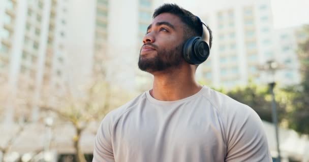 Mann, Denken und Musik mit Kopfhörern in der Stadt für ein Training, eine ruhige Übung oder ein Training. Sportler im Freien mit glücklichem Lächeln für Meditation, Fitness und Audio-Hören zur Motivation beim Laufen. - Filmmaterial, Video
